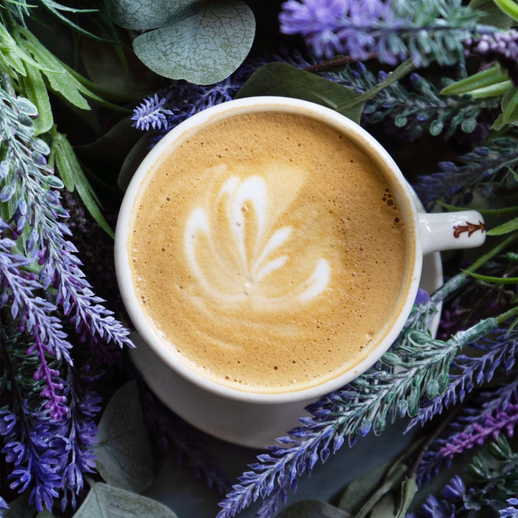 lavender oak milk latte on a table with lavender surrounding it