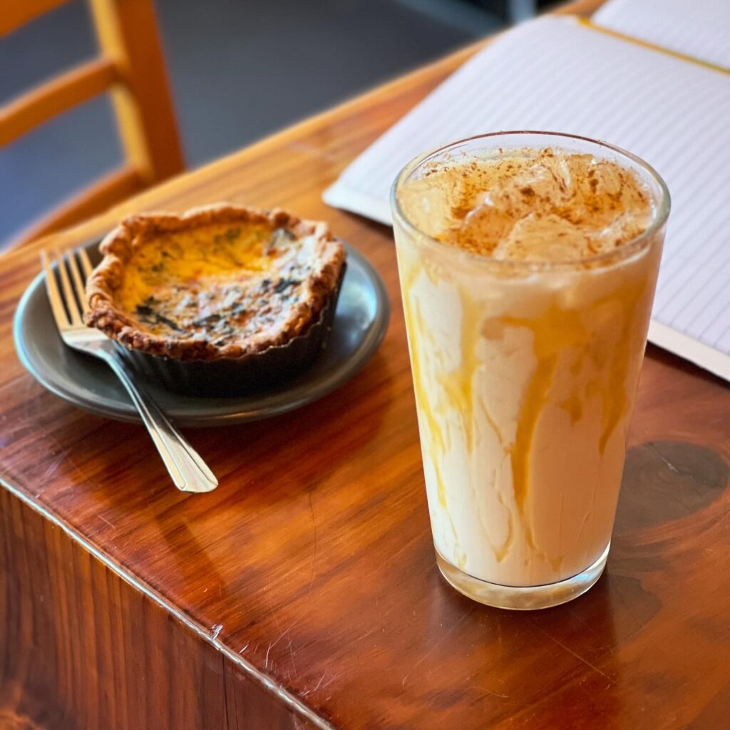 caramel chai latte with a quiche on a wooden table